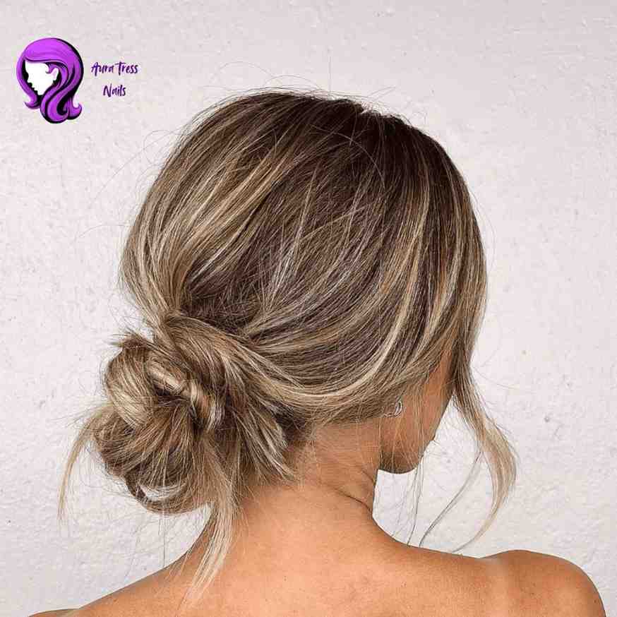 Woman with a high, messy bun, with loose strands for a soft, glamorous night-out look