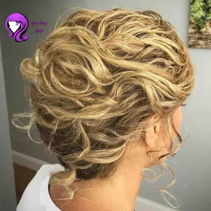 Woman with a curly french roll updo, creating a bouncy, elegant hairstyle for the evening