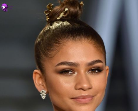 A stylish messy top knot hairstyle inspired by Zendaya, with loose strands framing the face for a casual yet chic look.