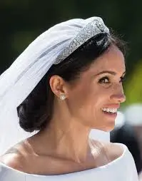 Elegant low chignon with loose face-framing tendrils, inspired by Meghan Markle's bridal look.